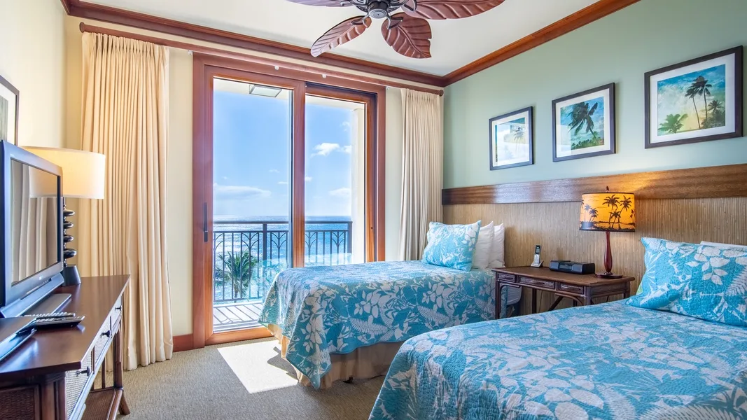 A bedroom with two beds dressed in blue patterned bedding beside a balcony door.