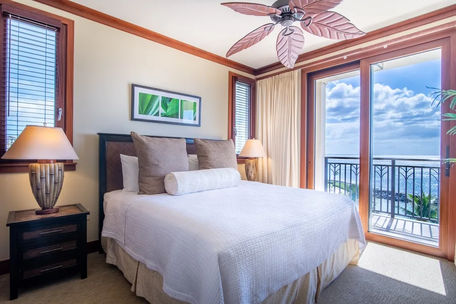A bedroom with a neatly made bed and sliding glass doors opening onto a balcony.