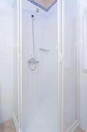 Una ducha de baño luminosa con paredes blancas y una ducha de mano.