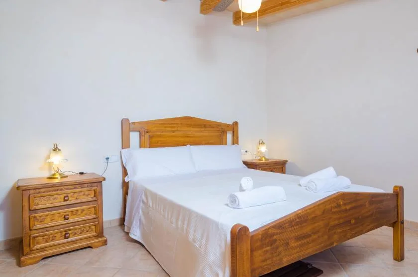 Un dormitorio con cama de madera, ropa de cama blanca y muebles de noche a juego.