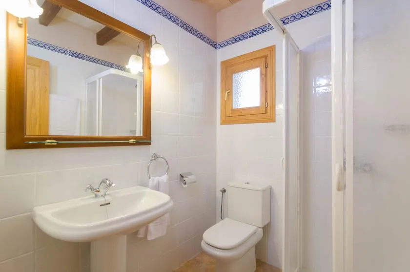 Un baño alicatado con lavabo, inodoro y ducha con mampara de vidrio.