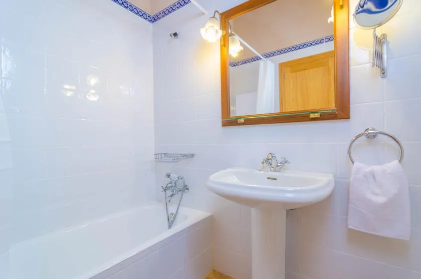 Un baño alicatado con bañera, lavabo y espejo de pared.
