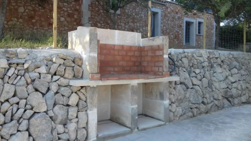 Una encimera de mampostería al aire libre está junto a un muro de piedra.