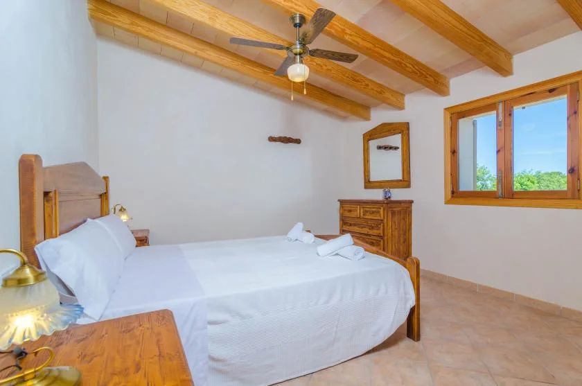 Un dormitorio con una cama bien hecha y un techo con vigas de madera.