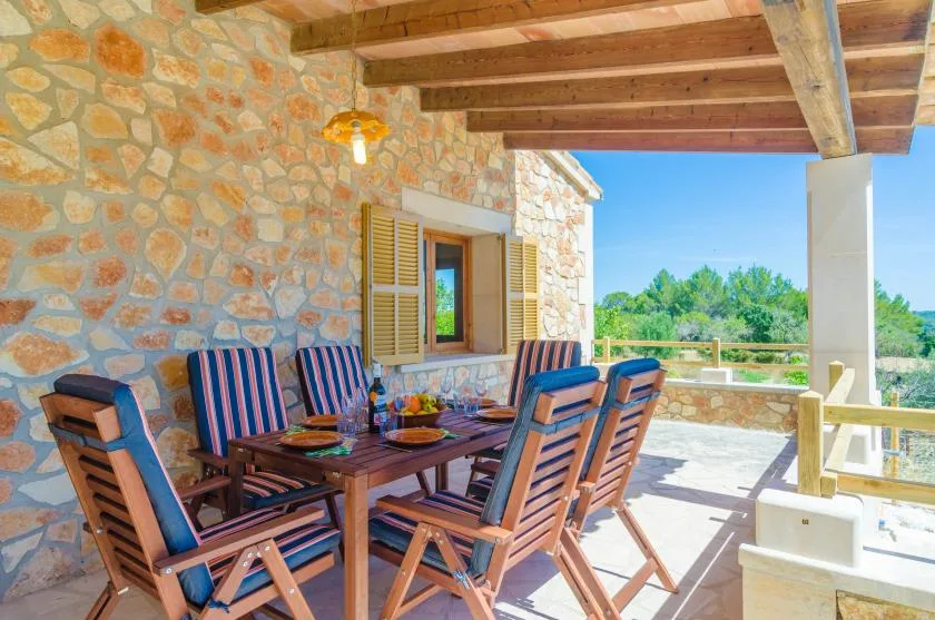Un comedor al aire libre con asientos de madera bajo una terraza cubierta.