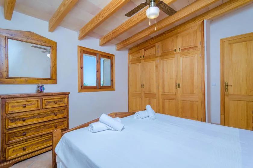 Un dormitorio con cama, armarios de madera y vigas de techo a la vista.