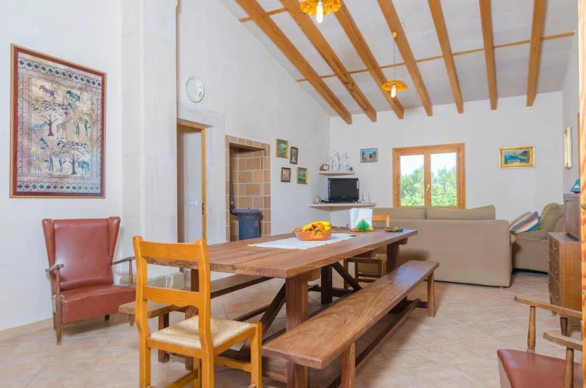 Comedor con una mesa larga de madera y asientos, junto a una sala de estar.