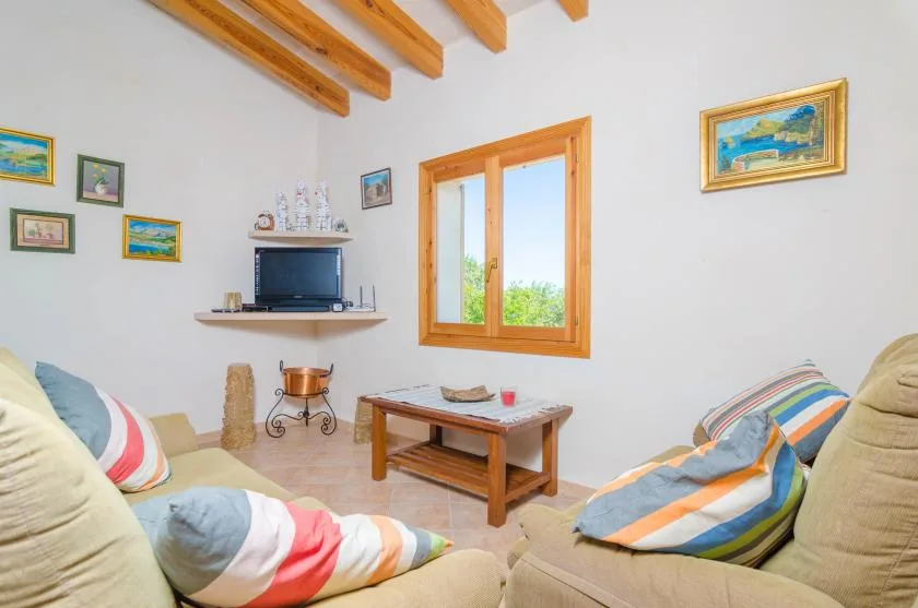 Una sala de estar luminosa con asientos acolchados, una mesa de centro de madera y una ventana.