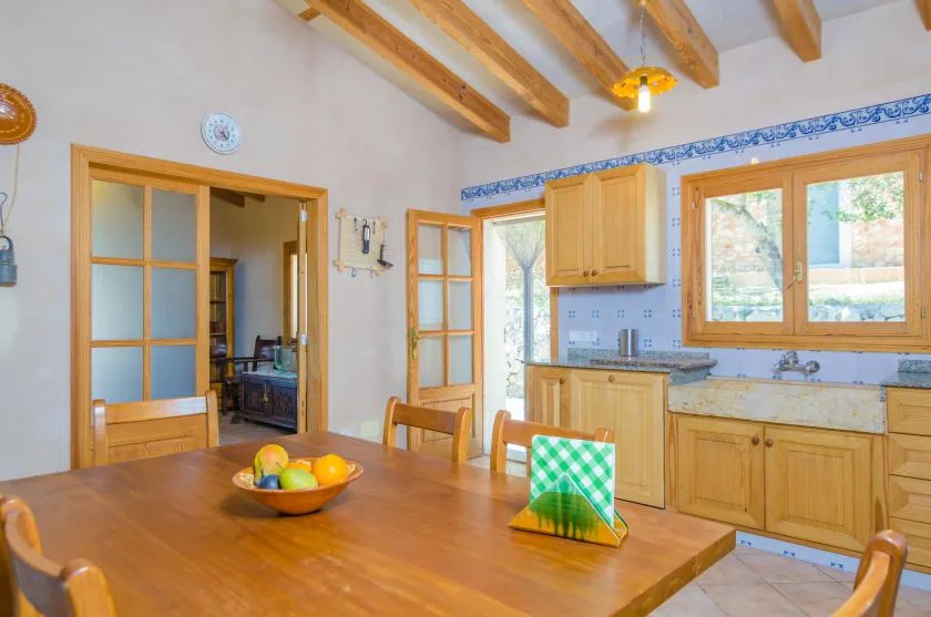 Un comedor con una mesa y sillas de madera está junto a una cocina.
