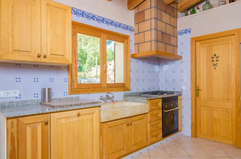 Una cocina luminosa con armarios de madera, una encimera y una ventana.