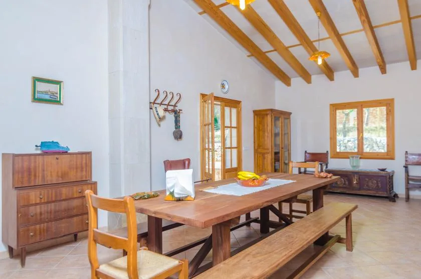 Un comedor con una mesa larga de madera y vigas expuestas en el techo.