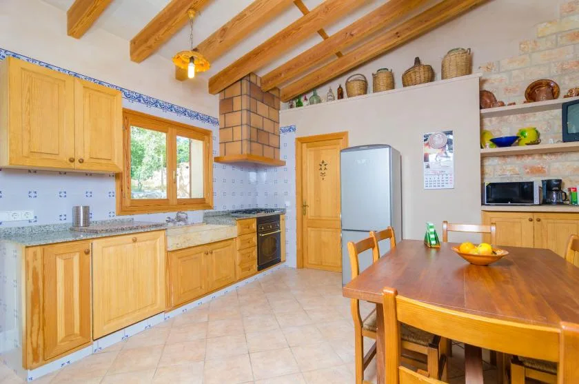 Una cocina luminosa con armarios de madera, una mesa de comedor y vigas expuestas.