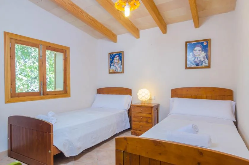 Un dormitorio con dos camas, vigas de madera en el techo y una ventana.