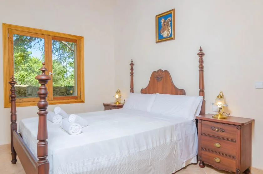 Un dormitorio con una cama grande de madera y una ventana con vistas a la vegetación.