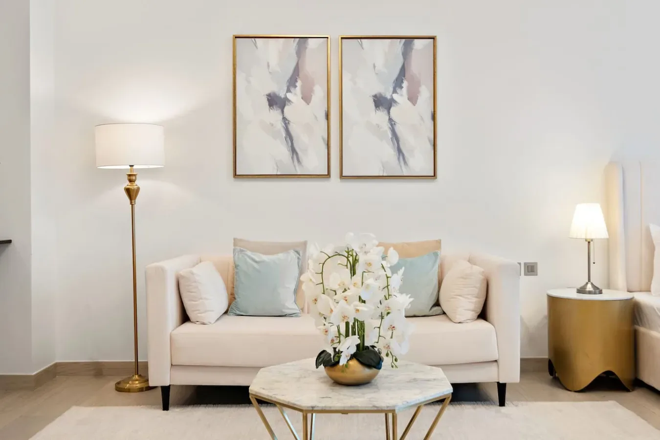 Una sala luminosa presenta un sofá claro y un arreglo floral sobre una mesa de centro.