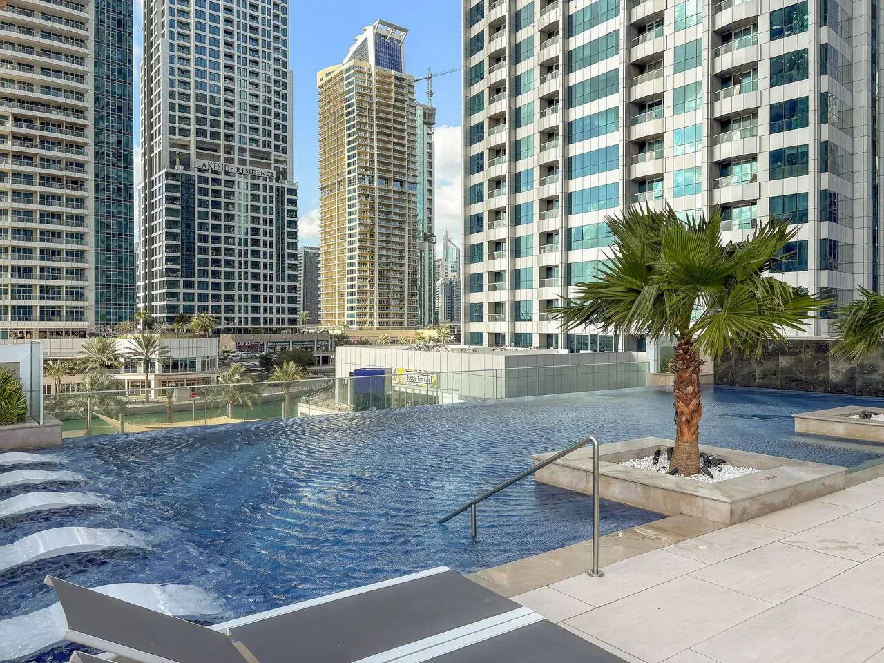 Una piscina al aire libre está rodeada de edificios altos y zonas pavimentadas.