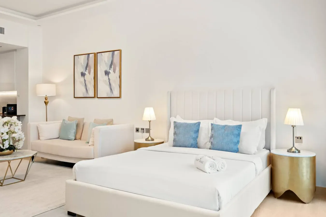 Un dormitorio luminoso cuenta con una cama grande con cojines azules y una zona de estar.