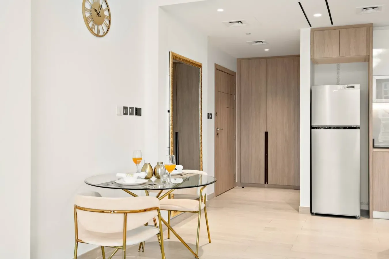 Un comedor luminoso con una mesa redonda y una cocina compacta al fondo.