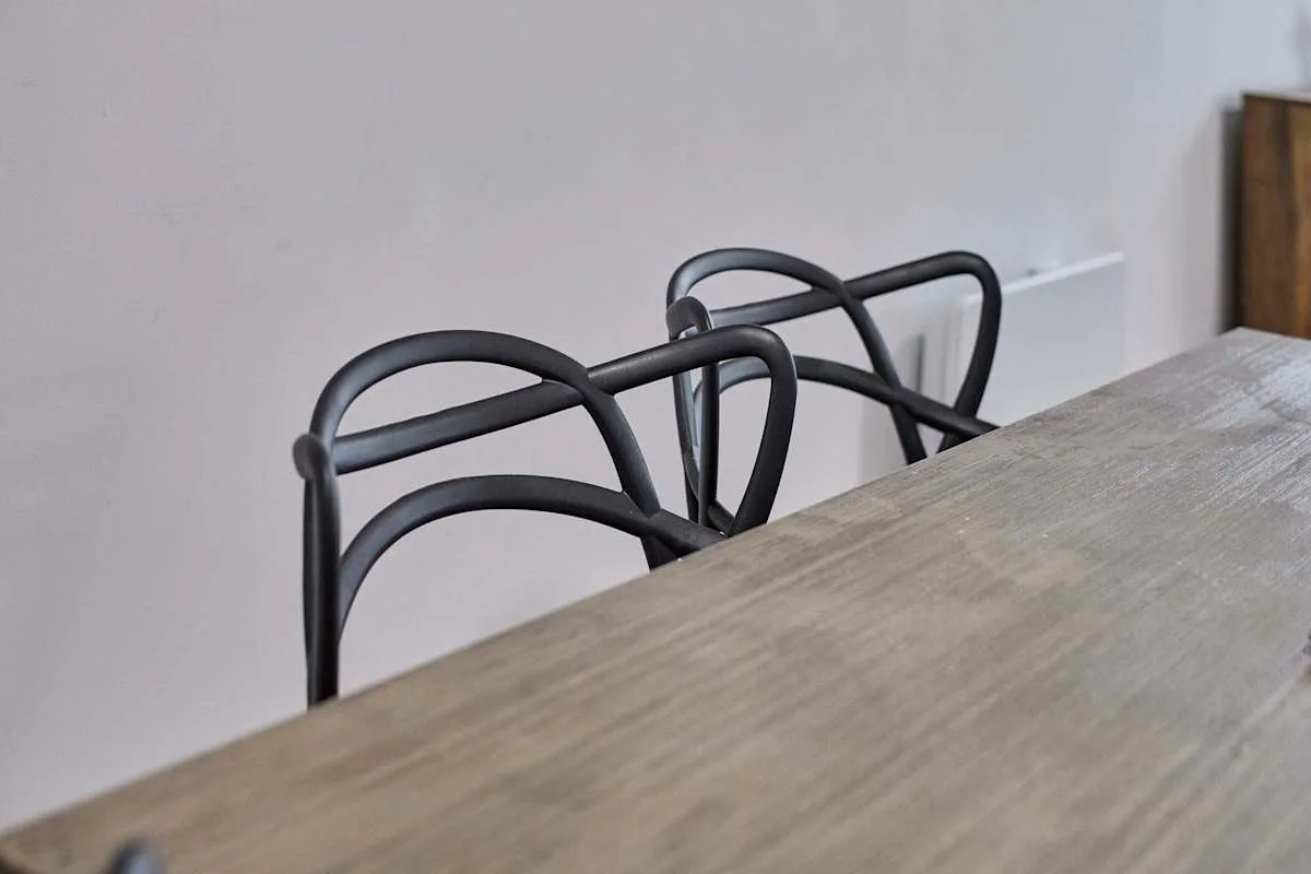 Dining area with a table and black chairs against a light wall.