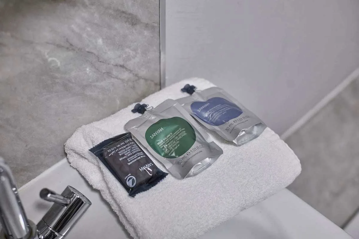 A folded towel with toiletry packets rests beside a bathroom sink.
