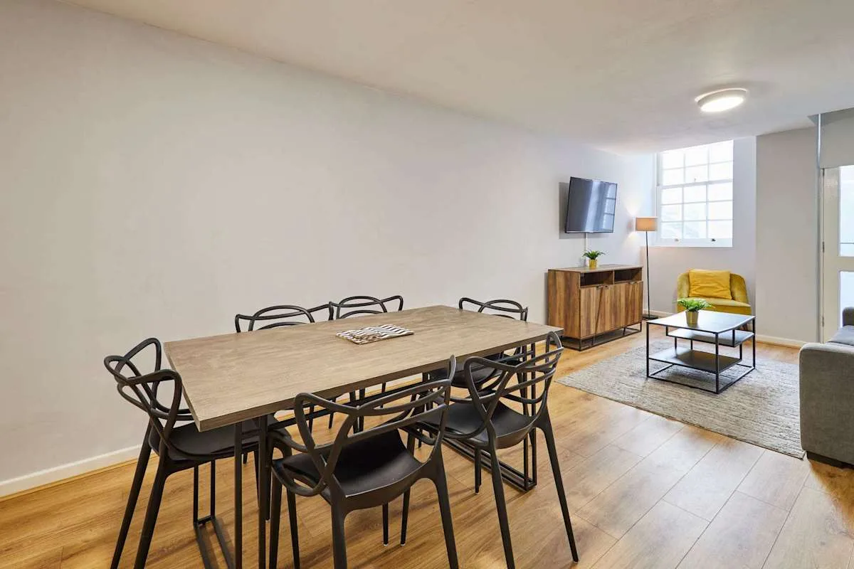 Dining and living area with a wooden table and seating by the window.