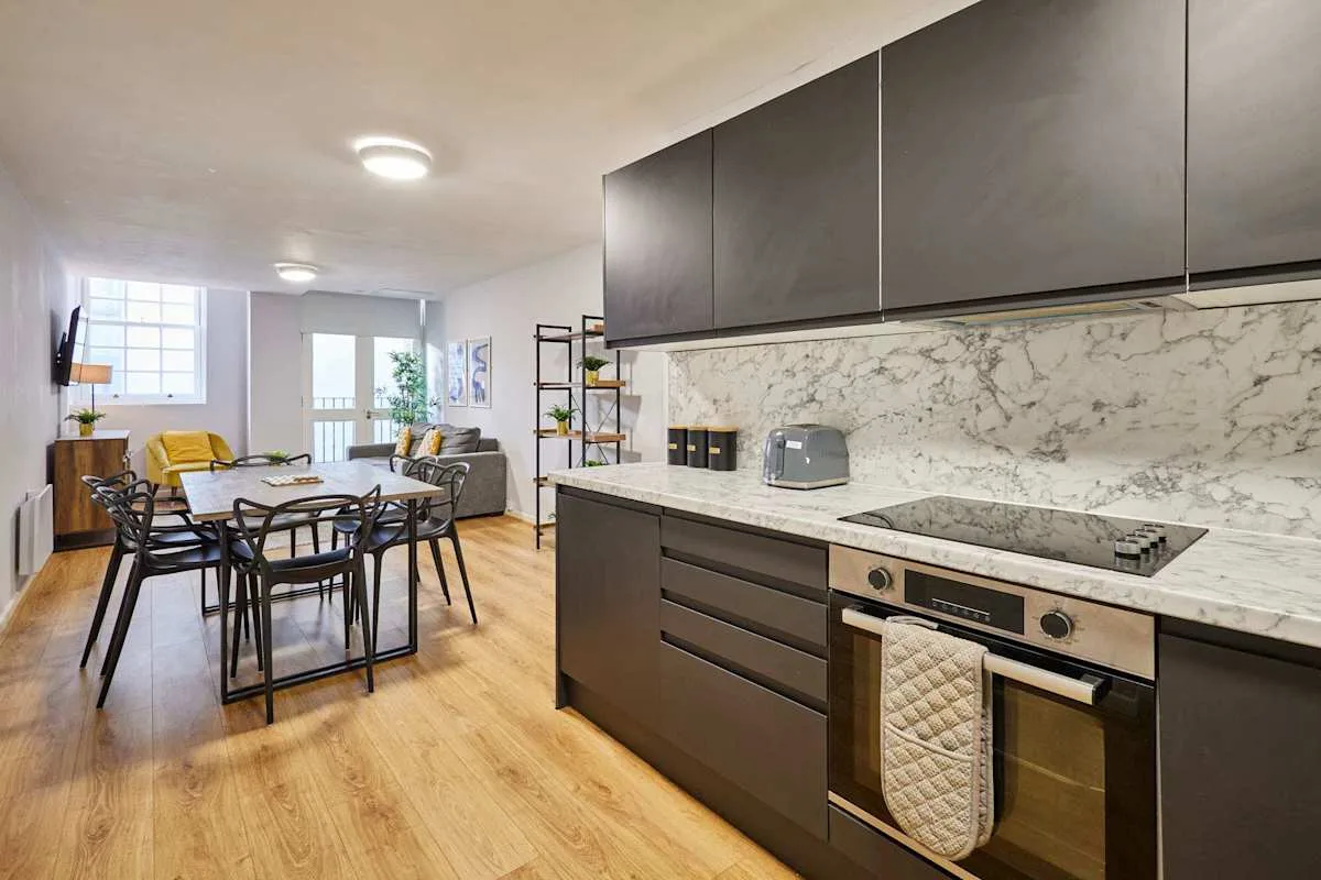 An open-plan kitchen and dining area with dark cabinets and a dining table.