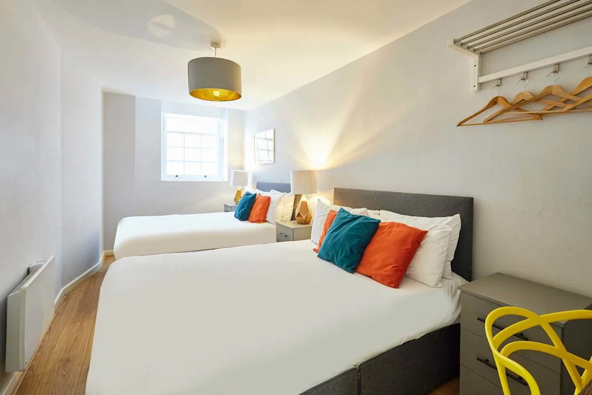 A bright bedroom with two beds and a window.