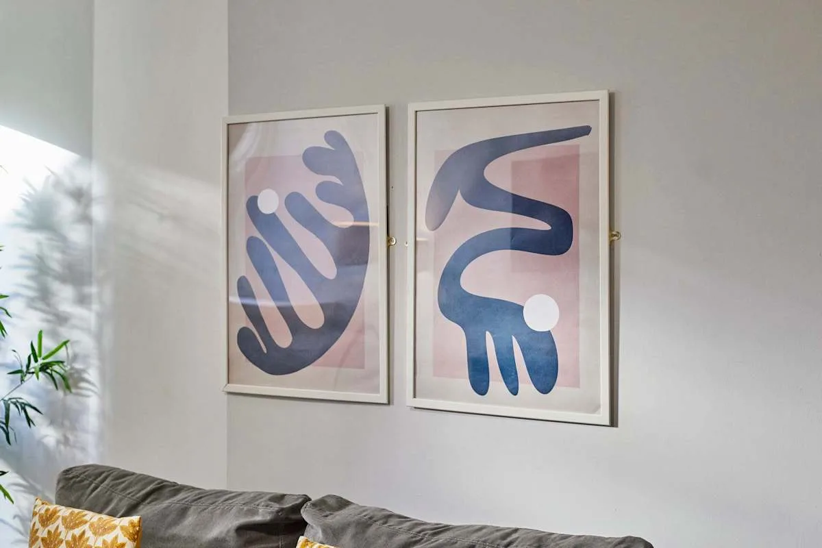 A living room with a gray sofa beneath two framed abstract prints.