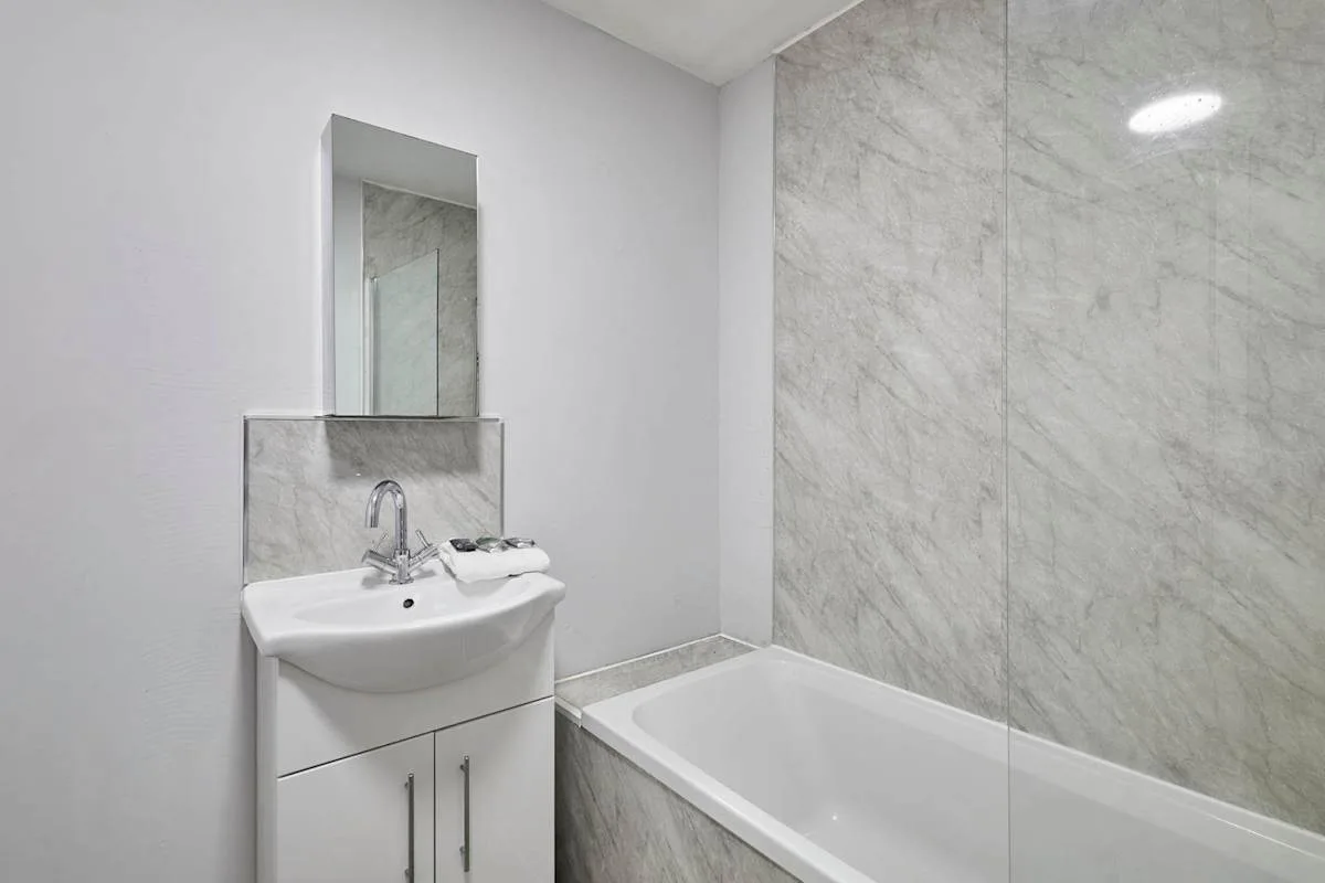 A bathroom with a sink, mirror, and bathtub.