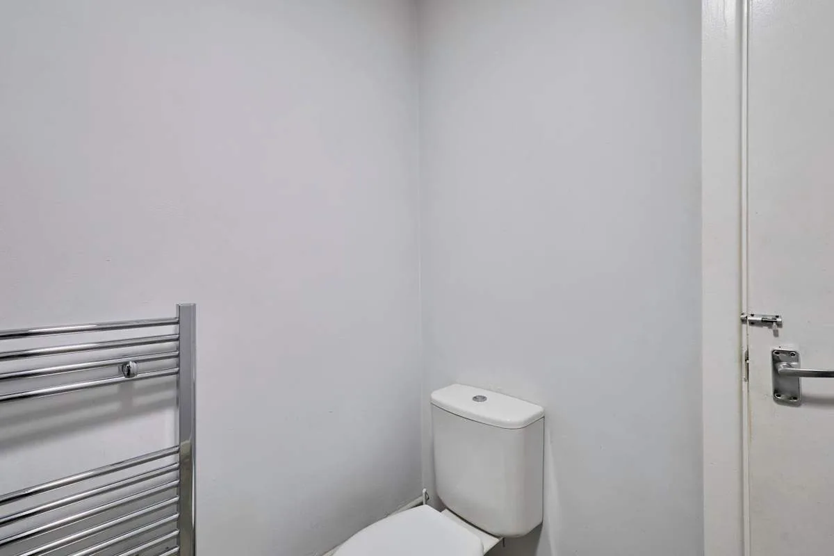 A bathroom with a toilet and a metal towel rail.