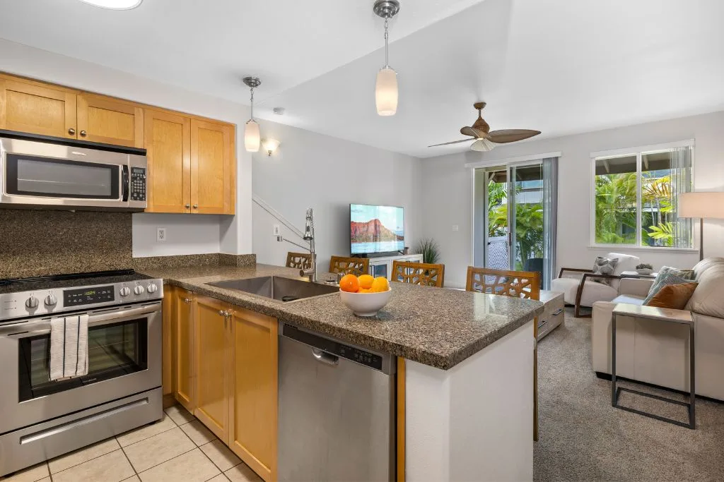 Cocina y sala de estar diáfanas, con una isla central y asientos junto a las ventanas.