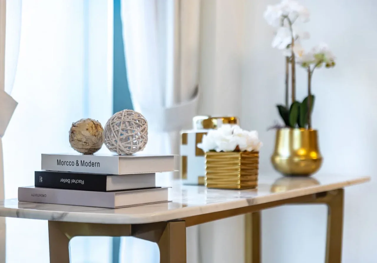Una escena interior luminosa con libros apilados, flores y objetos decorativos sobre una mesa.