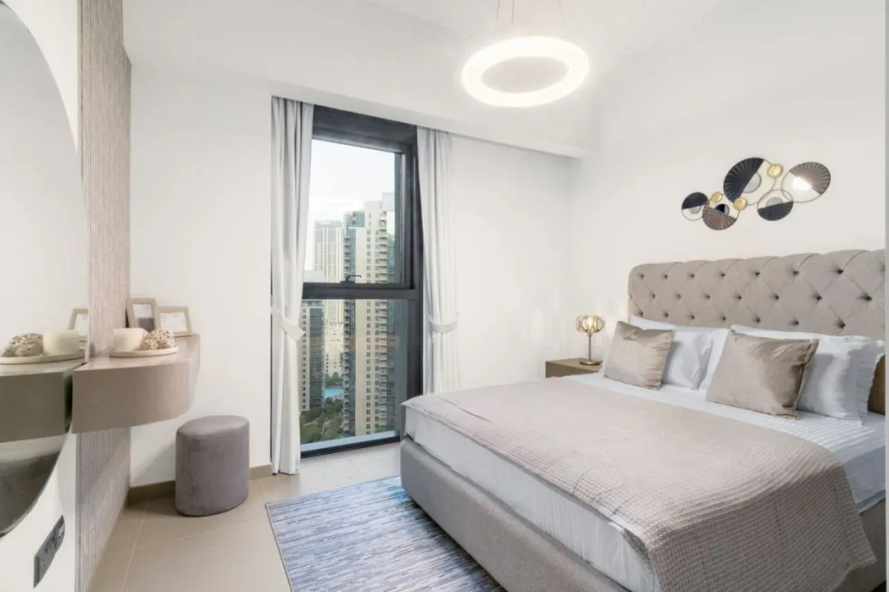 Un dormitorio luminoso con una cama amplia, mesillas y una ventana de suelo a techo.