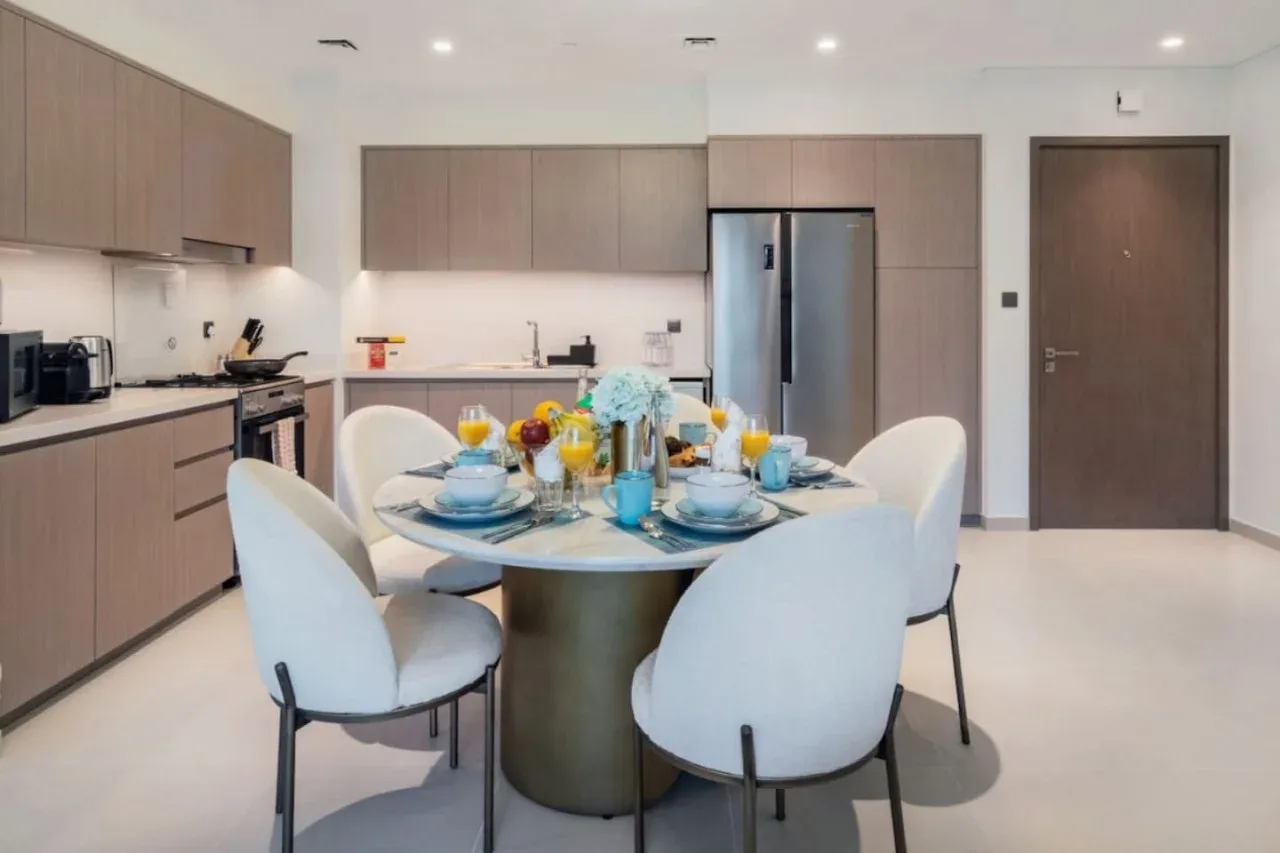 Una cocina y comedor modernos con la mesa puesta y asientos blancos.