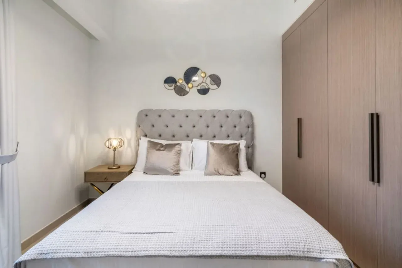 Un dormitorio con una cama, un cabecero capitoné y un armario.