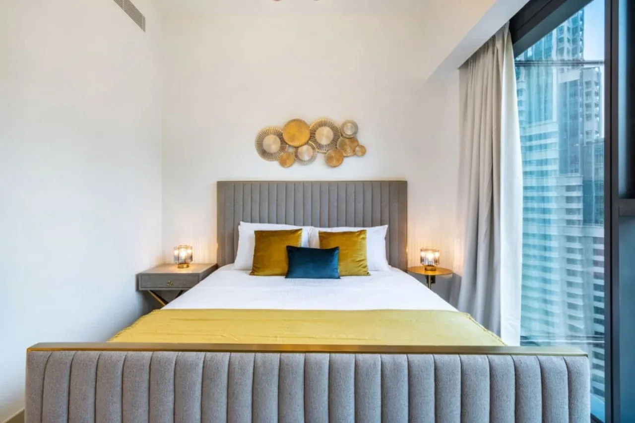Un dormitorio con una cama bien tendida y cojines decorativos dorados.