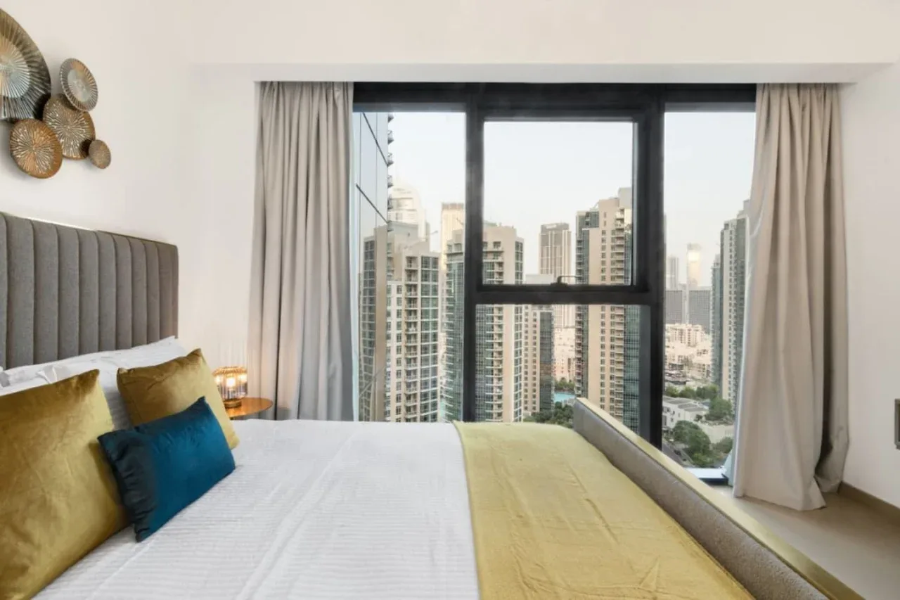 Un dormitorio con una gran ventana con vistas a edificios altos cercanos.
