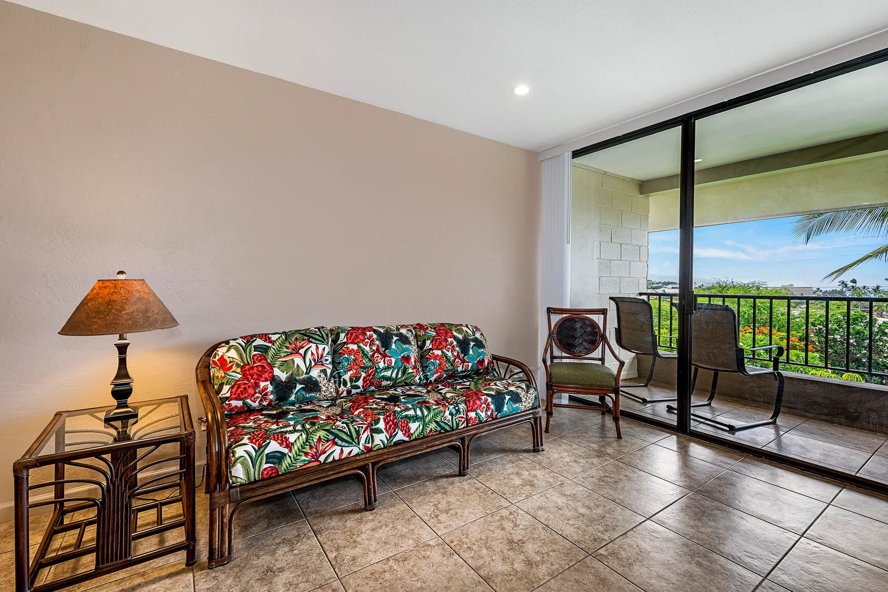 A living room with patterned seating beside sliding glass doors opening to a balcony.