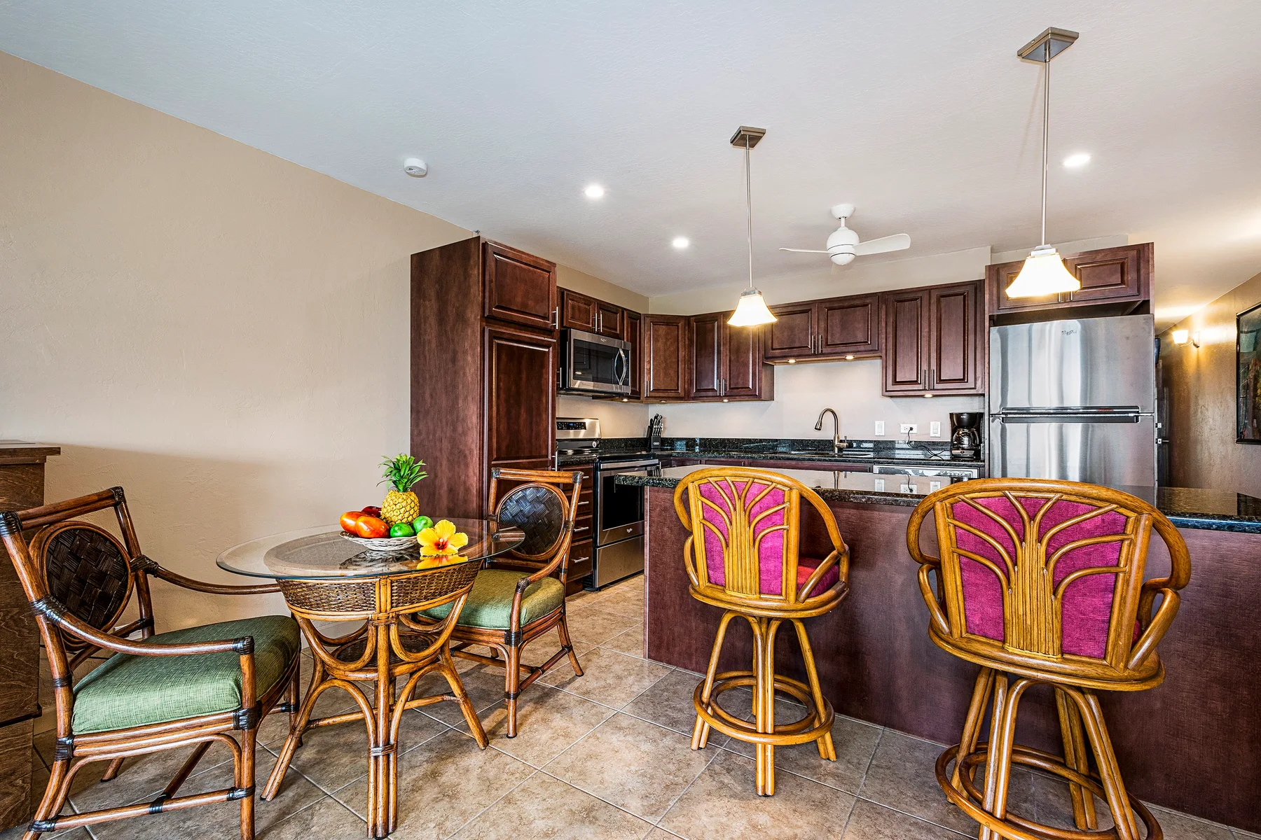 A kitchen and dining area with dark wood cabinets and colorful bar seating.