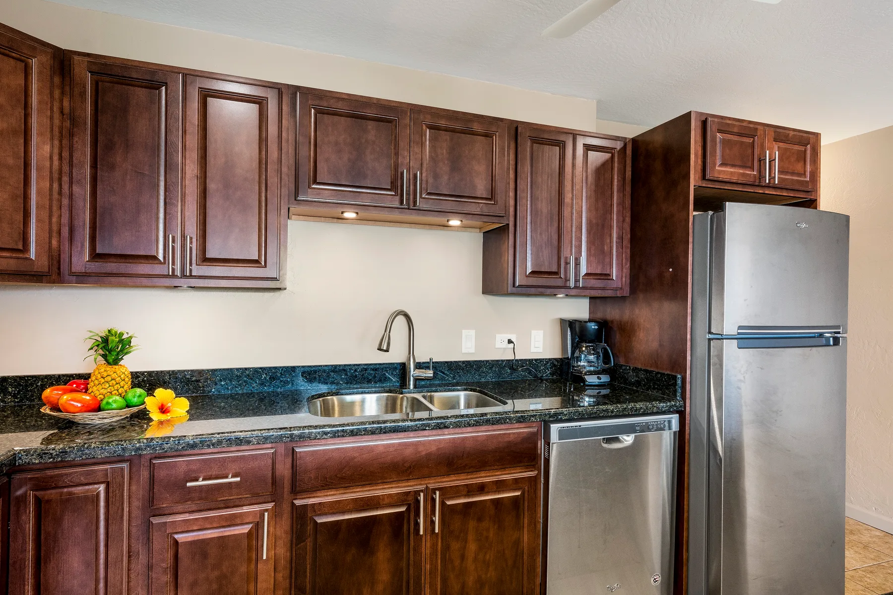 A kitchen with dark cabinetry, a countertop, sink, and stainless steel appliances.
