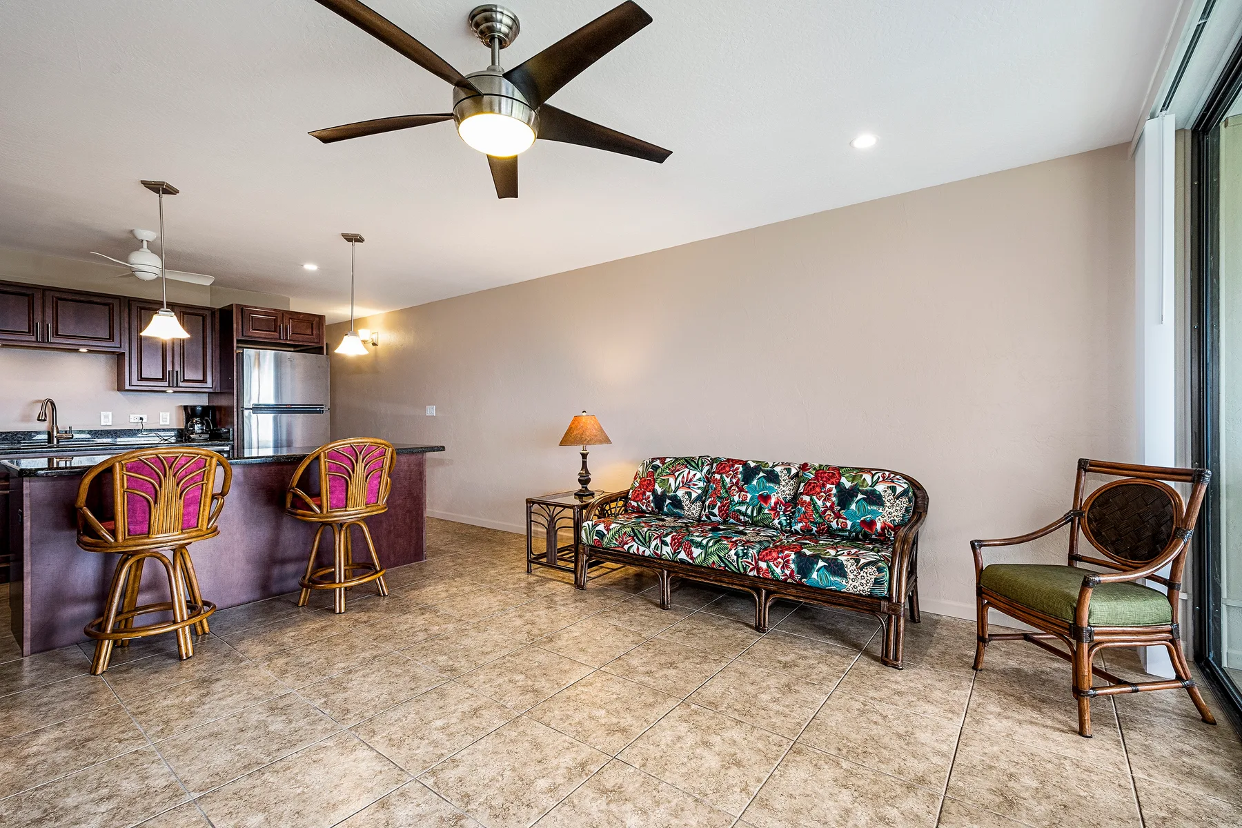 A living area with a floral-patterned sofa beside a kitchen bar.