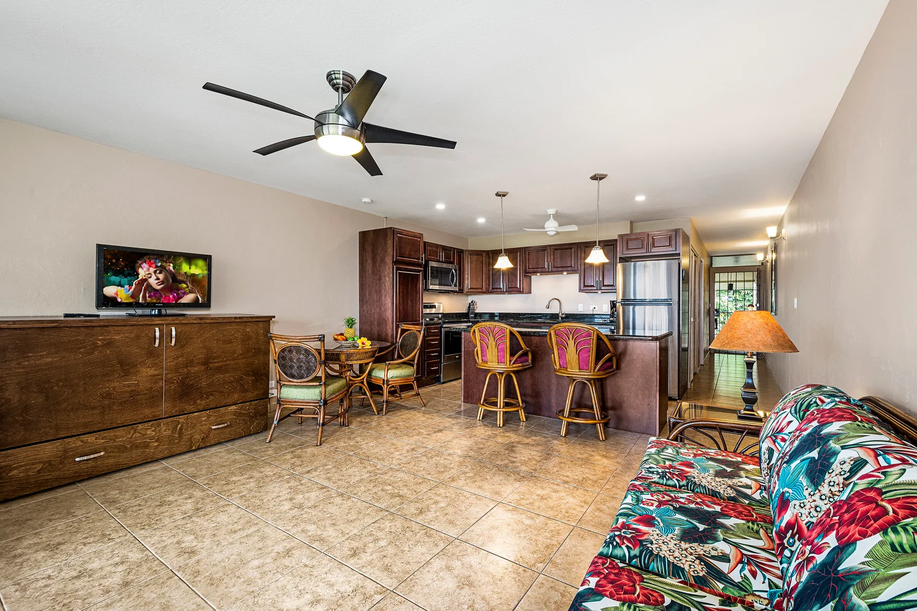 A living area opens onto a kitchen, with colorful seating and a dining table.