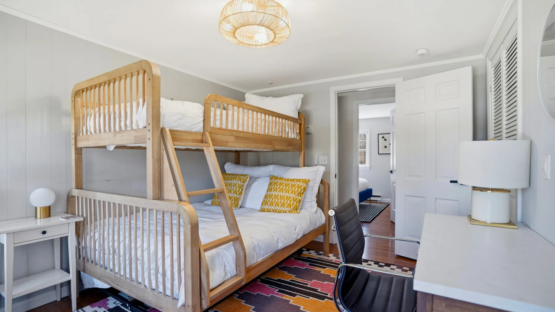A bright bedroom with wooden bunk beds and colorful patterned bedding.