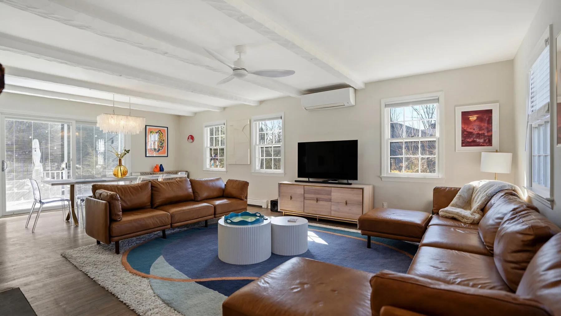 A bright living room with brown seating arranged around a television and coffee tables.