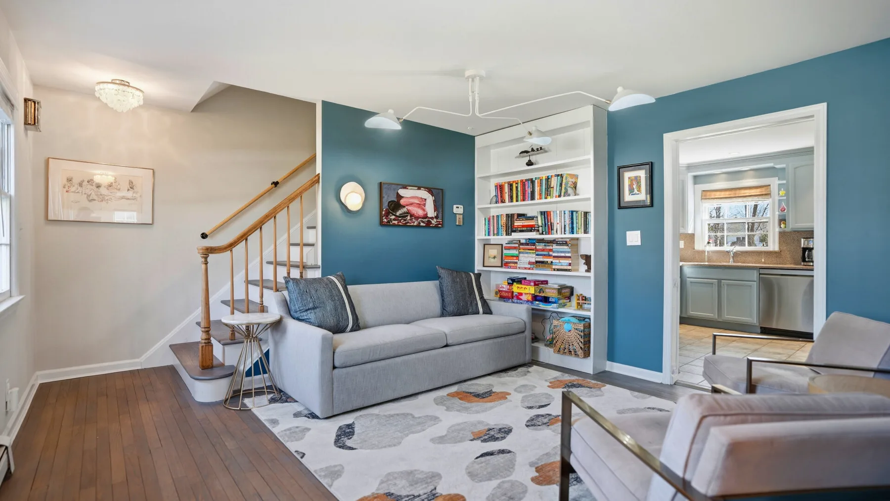 A living room with a gray sofa, colorful rug, and built-in bookshelves.