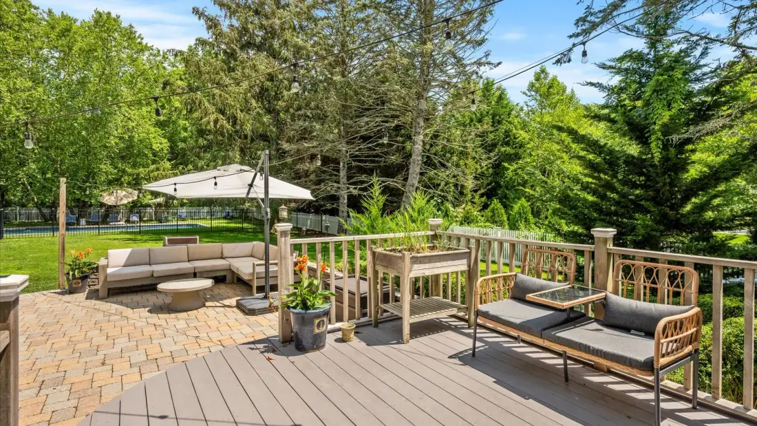 An outdoor patio with seating, a table, and surrounding trees.