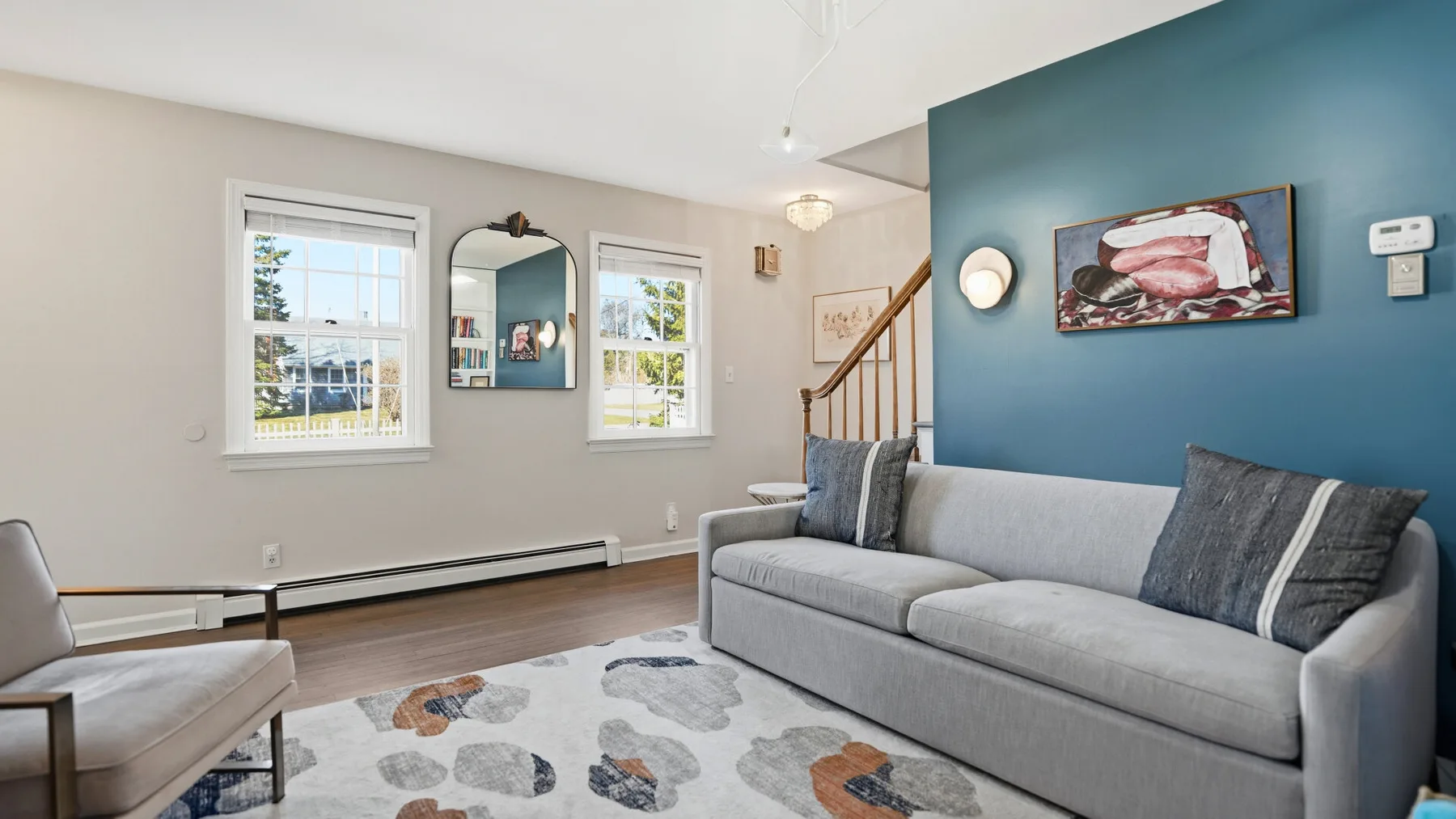 A living room with gray seating, a patterned rug, and a blue accent wall.