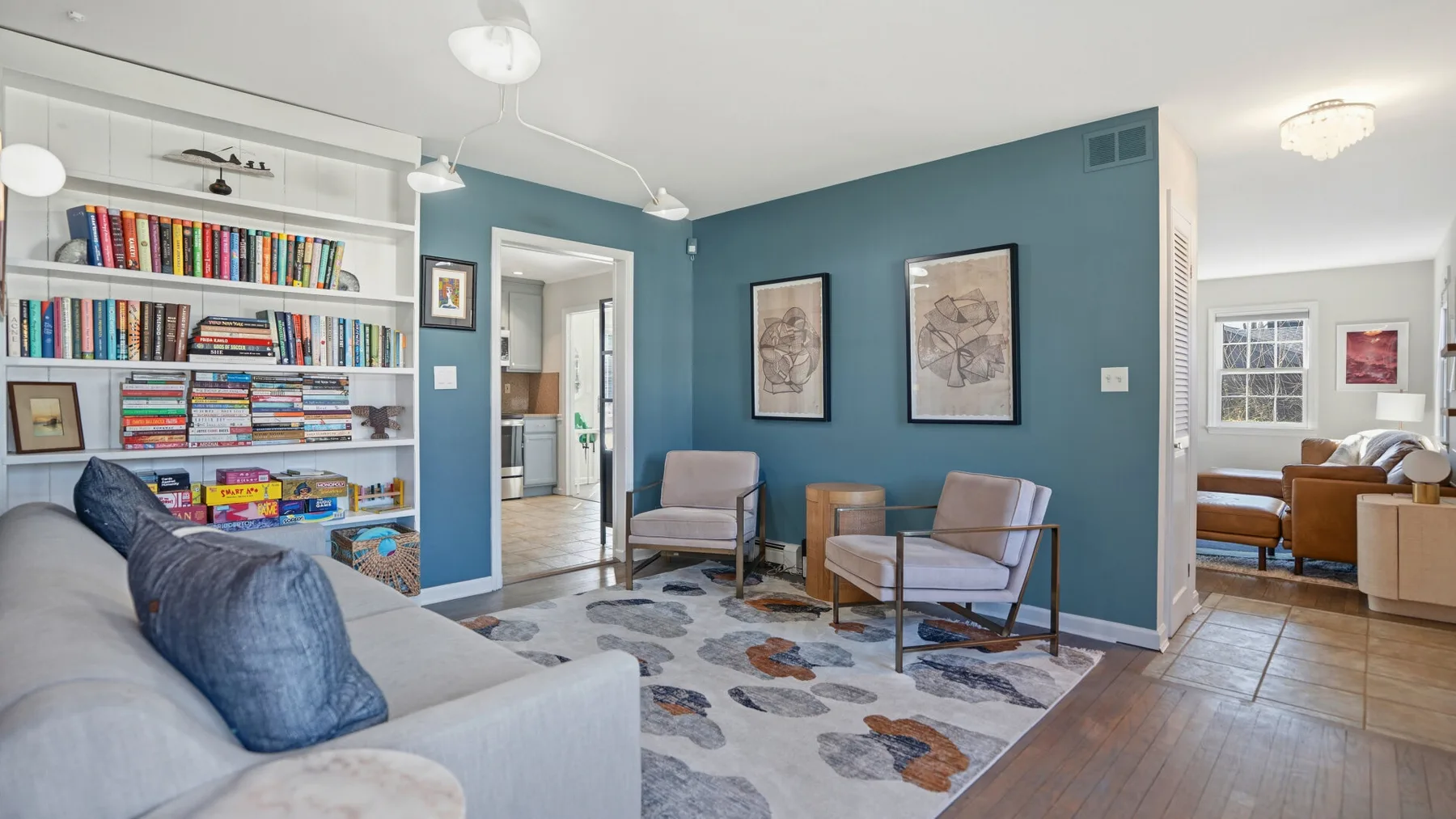 A living room with a bookcase, seating, and a patterned rug.