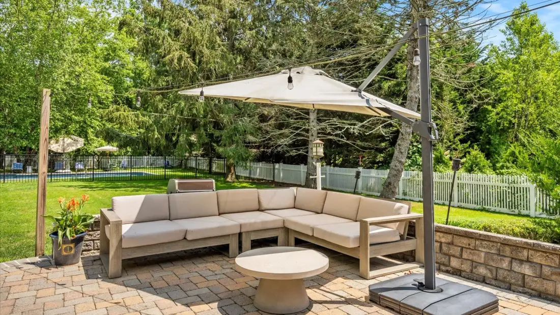 A paved outdoor patio with a sectional seating area beneath a large shade canopy.