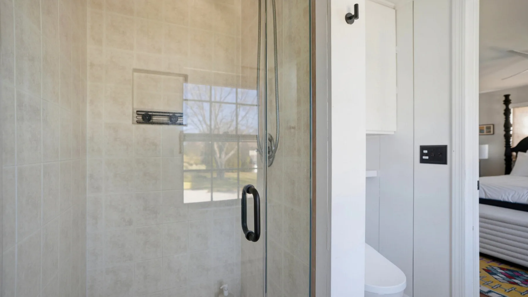 A bathroom with a glass shower beside a toilet.